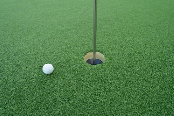 Hoyo de pelota de golf en canchas de pasto sintético en el campo de golf. Es una actividad deportiva y recreativa al aire libre.